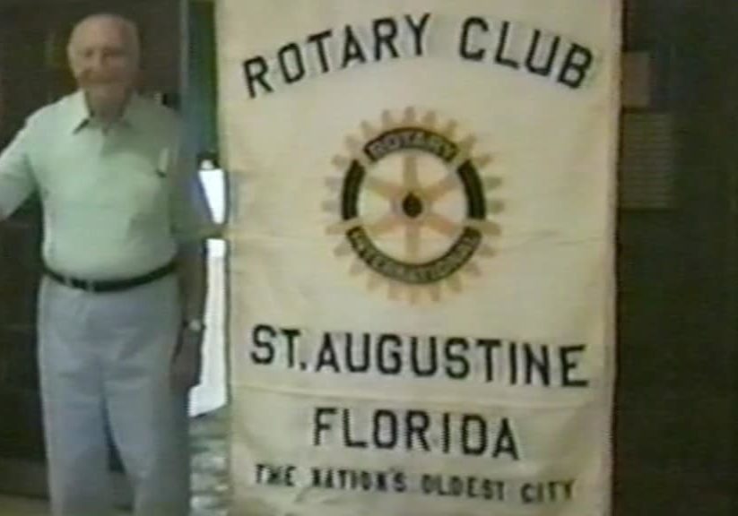 A member of the Rotary Club of St. Augustine stands in front of the club banner. Photo was taken in 1988.